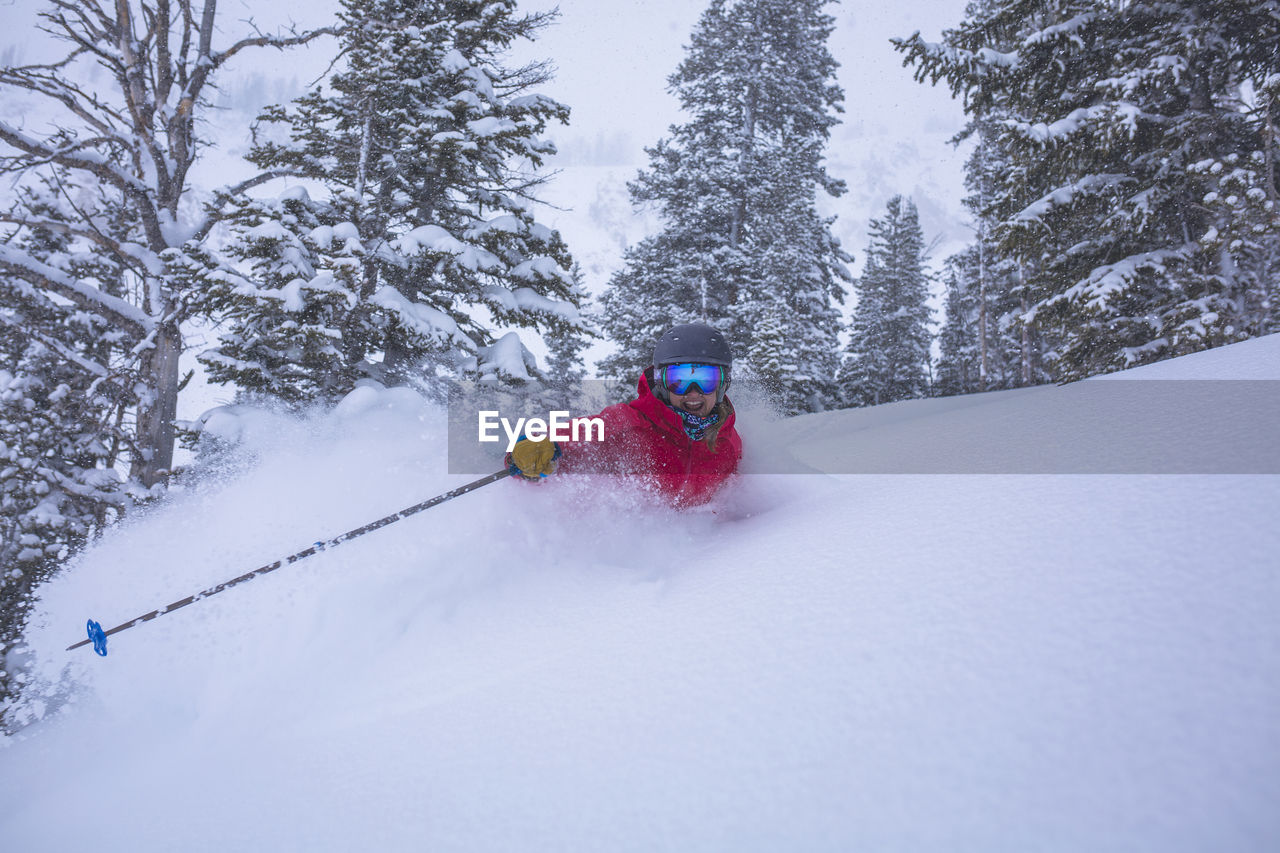 Cheerful woman skiing on snow covered landscape