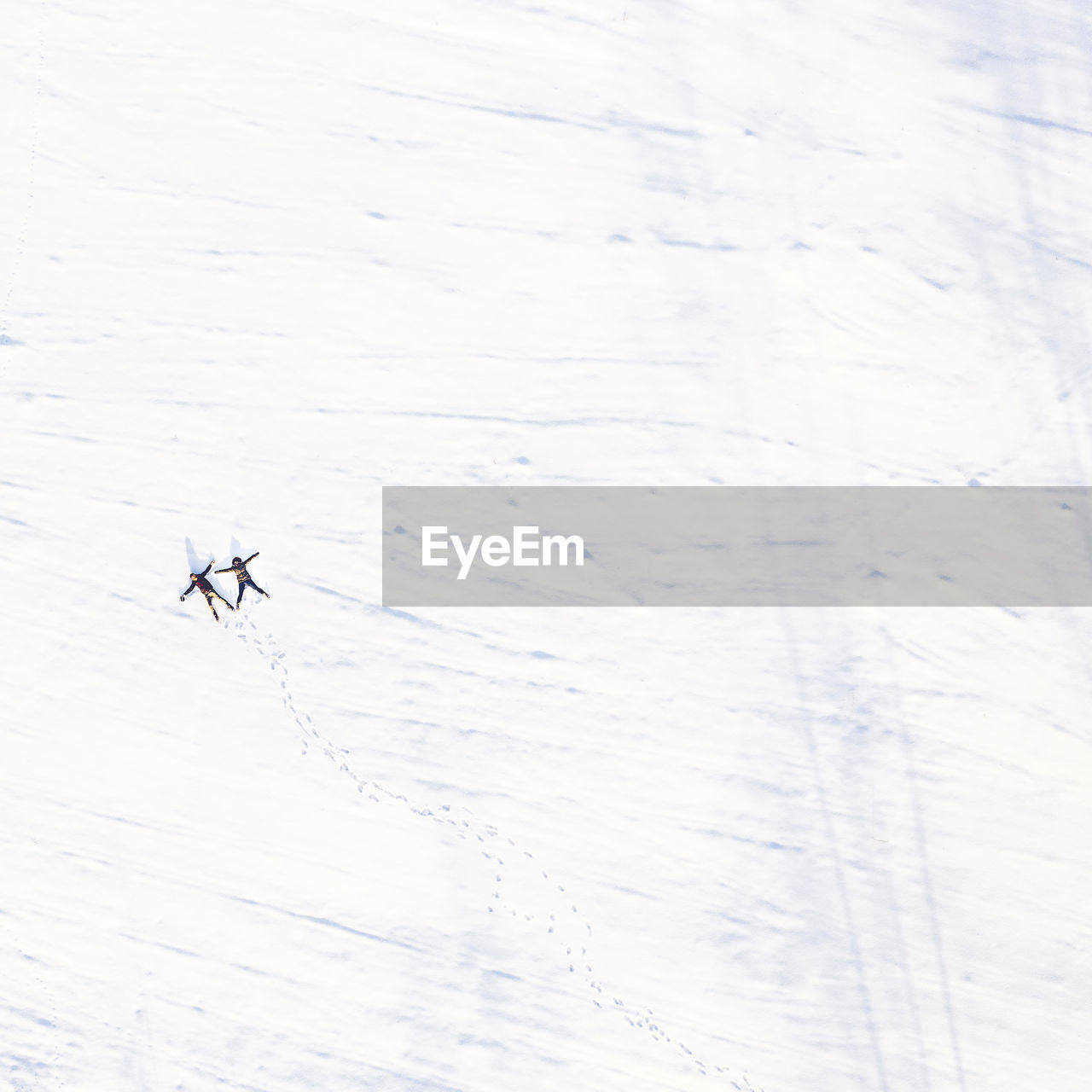 Aerial view of friends lying on snow covered field