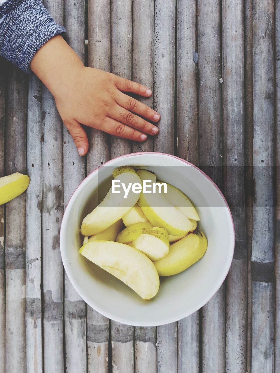 Cropped hand of child by pears in bowl on table