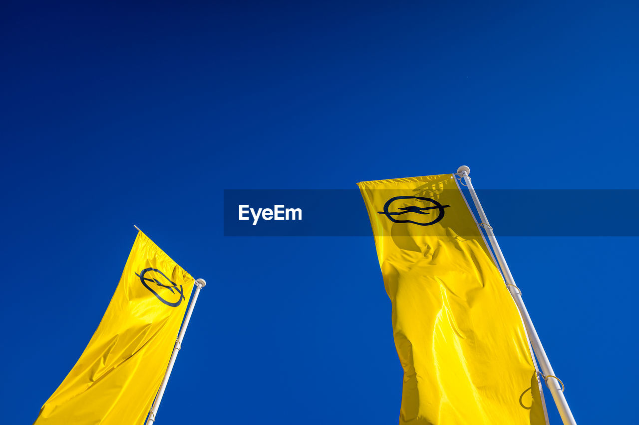 LOW ANGLE VIEW OF FLAGS AGAINST CLEAR BLUE SKY