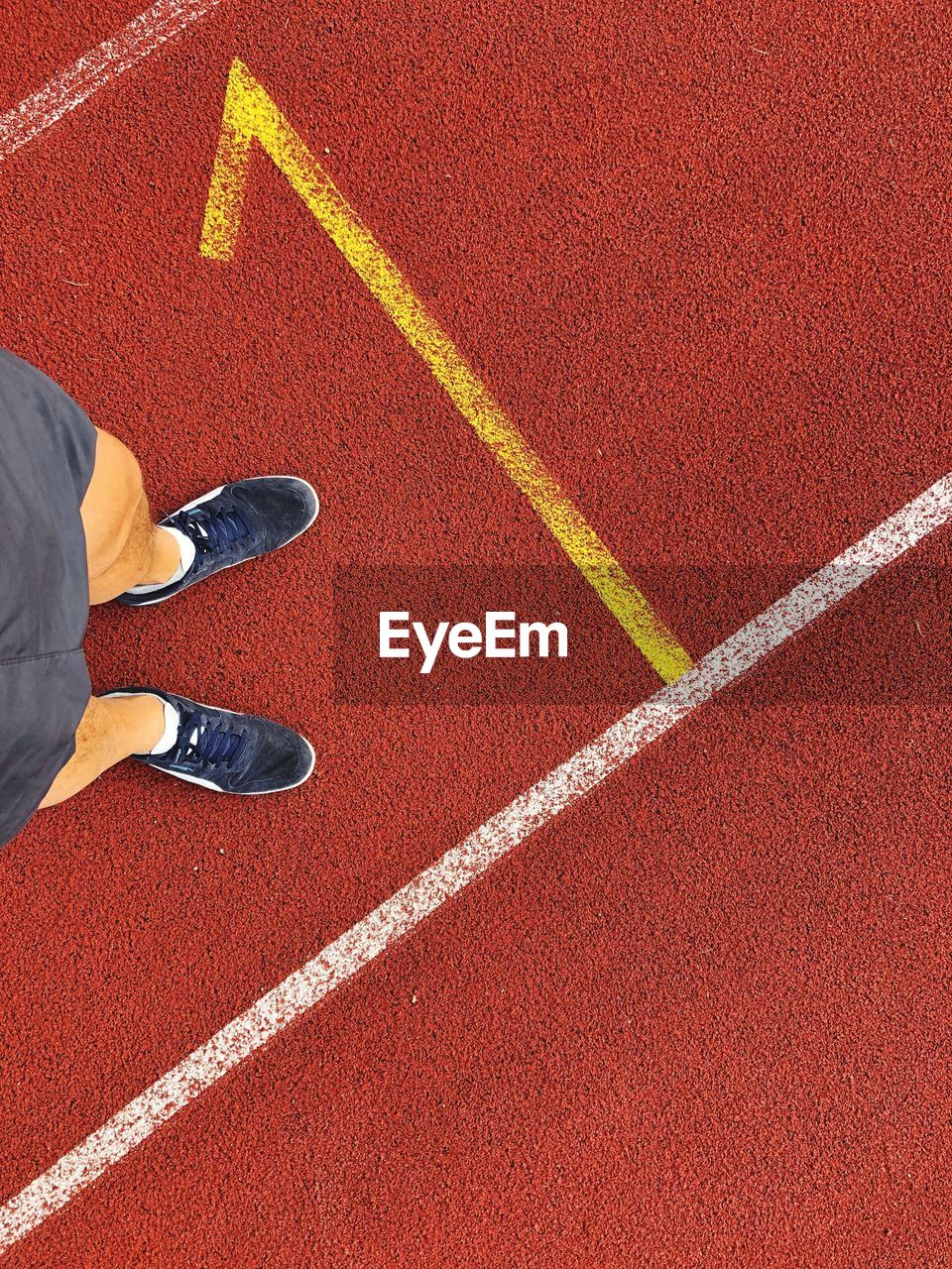 Low section of man standing on sports track