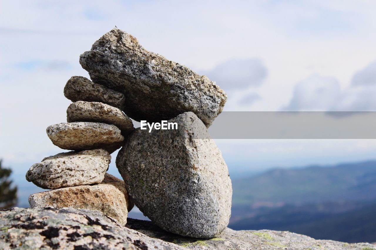 Stack of stones on rock against sky