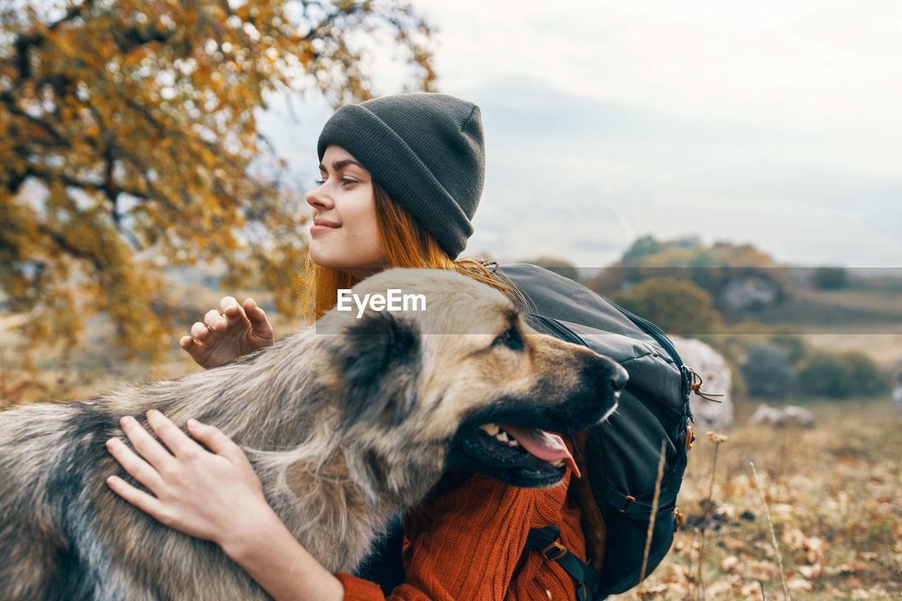 PORTRAIT OF YOUNG WOMAN WITH DOG IN BACKGROUND