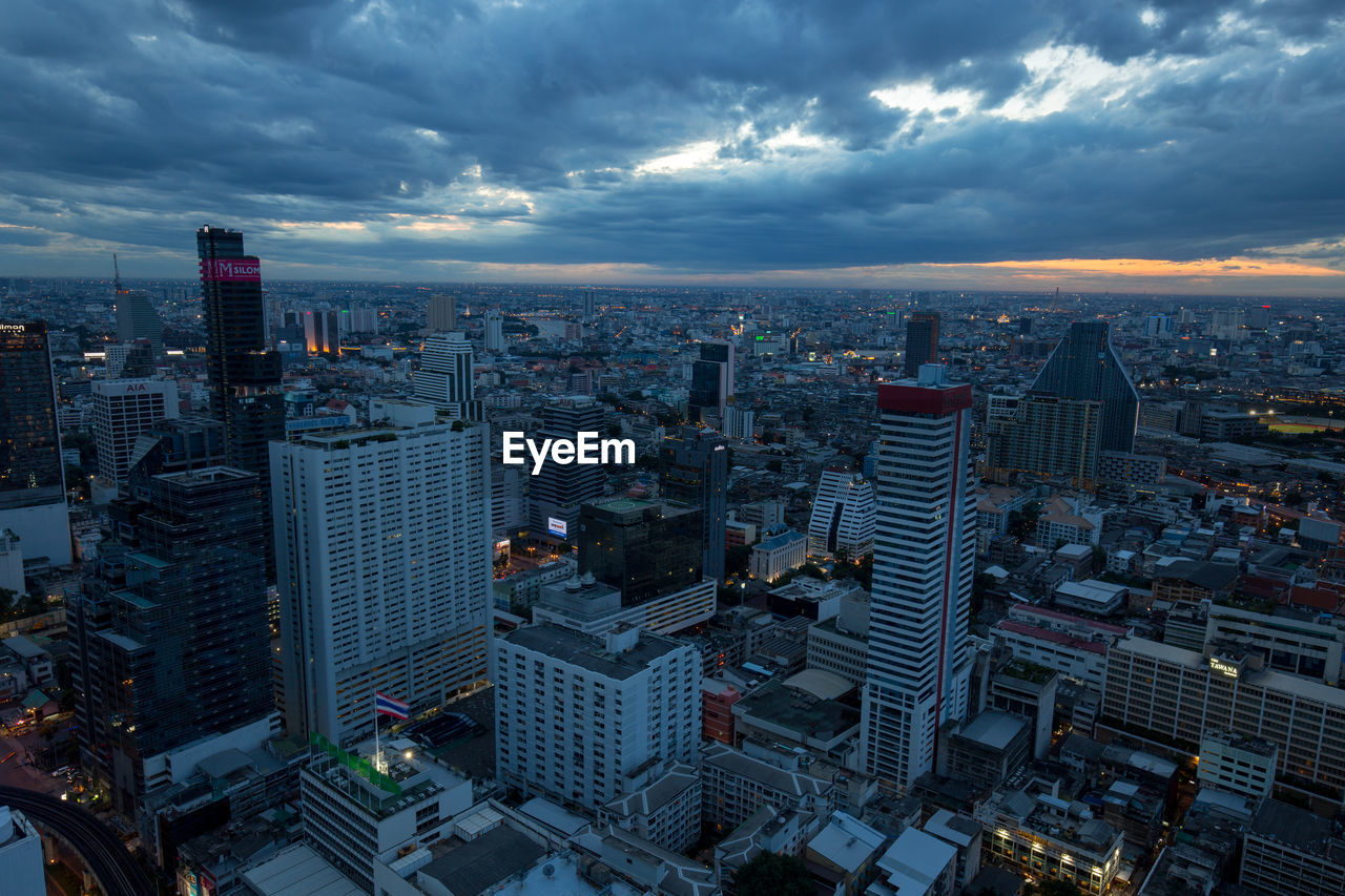 Aerial view of buildings in city against sky at dusk
