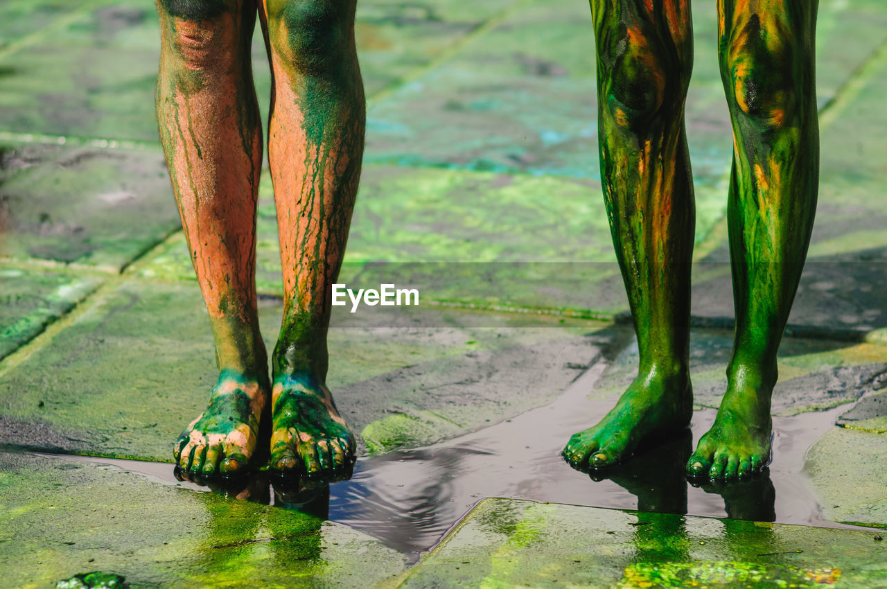 Legs of two people in a green paint during the festival of holi