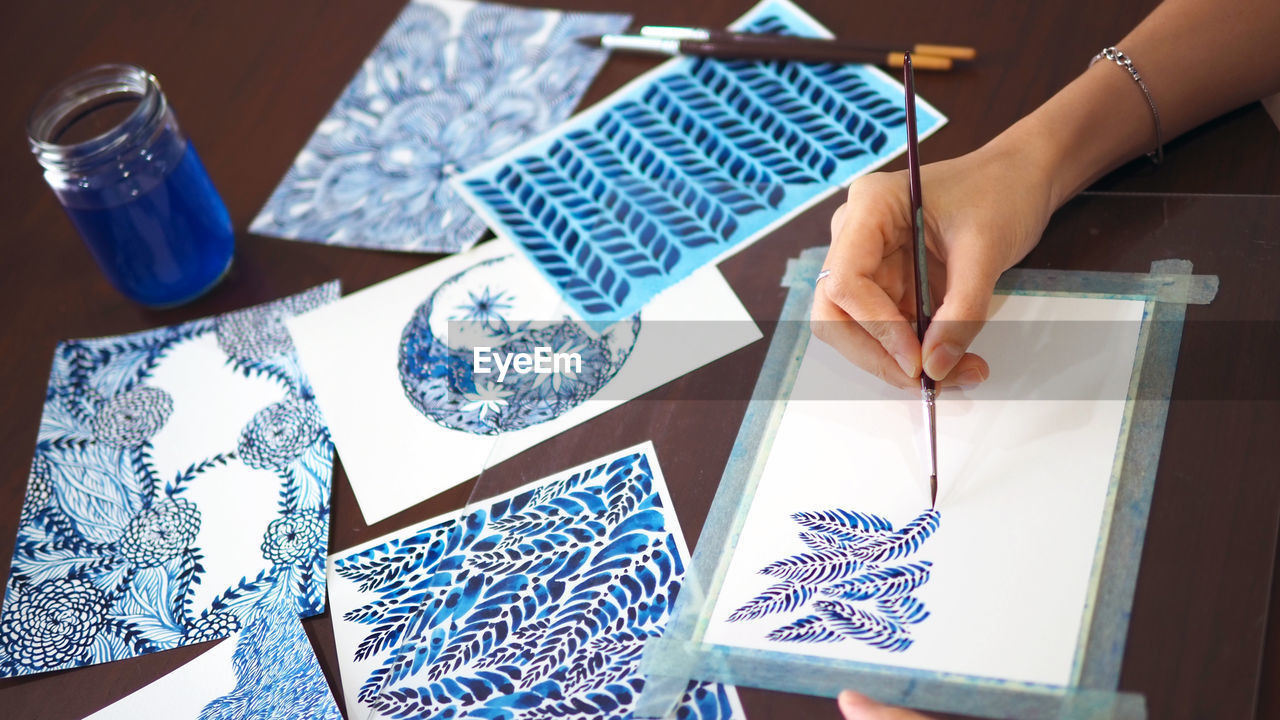 Cropped hand of woman making design on paper