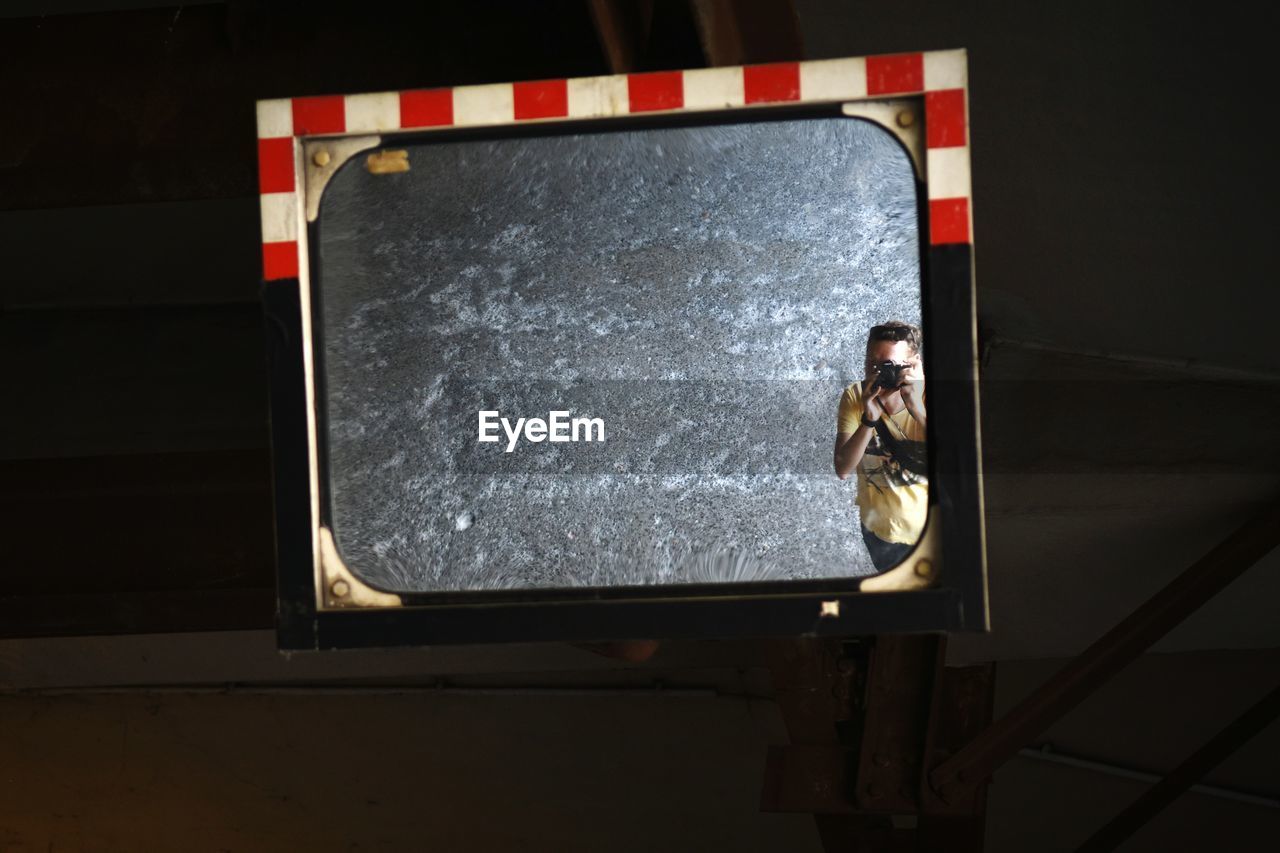 Man photographing on street with reflection in mirror