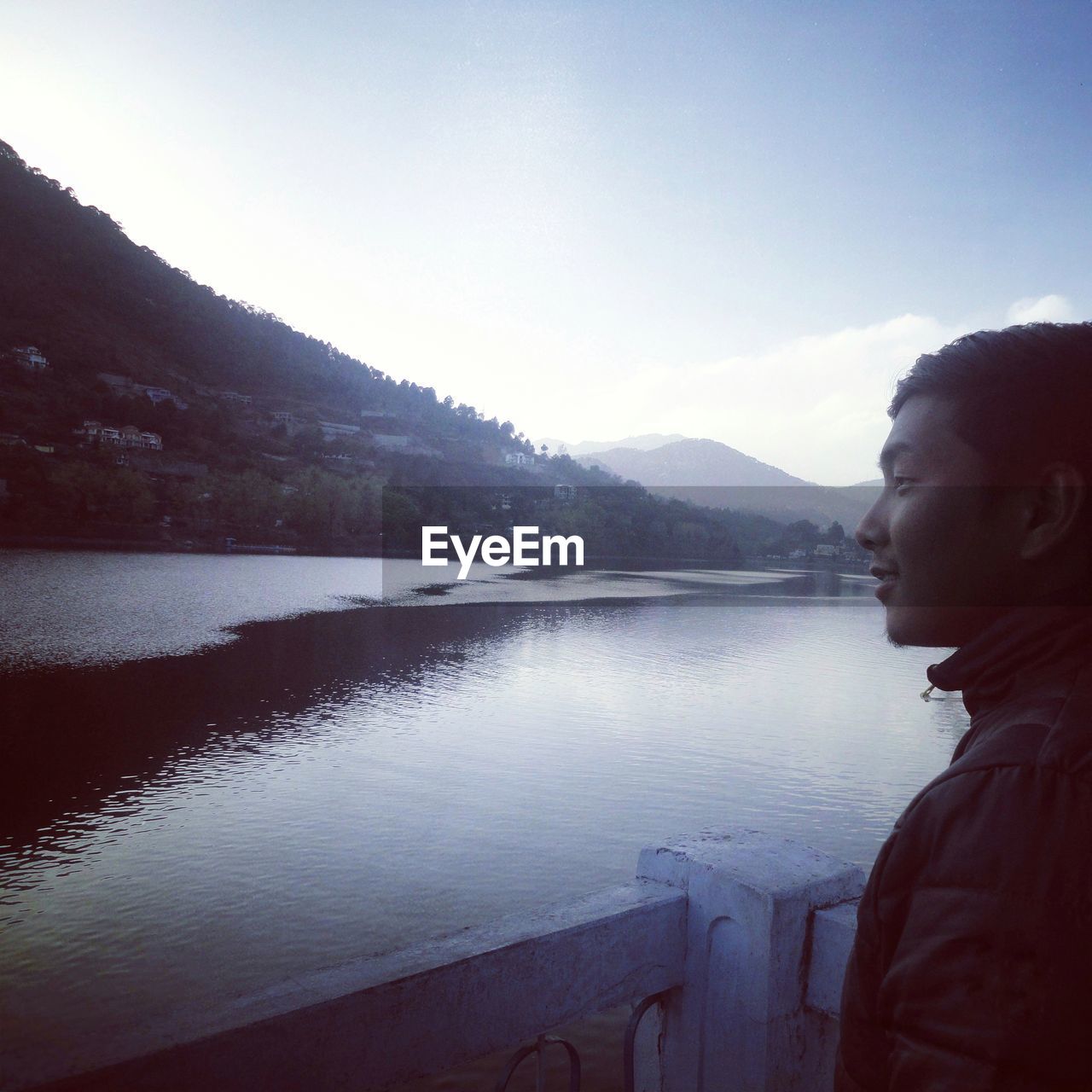 SIDE VIEW OF BEAUTIFUL YOUNG WOMAN STANDING BY LAKE AGAINST SKY