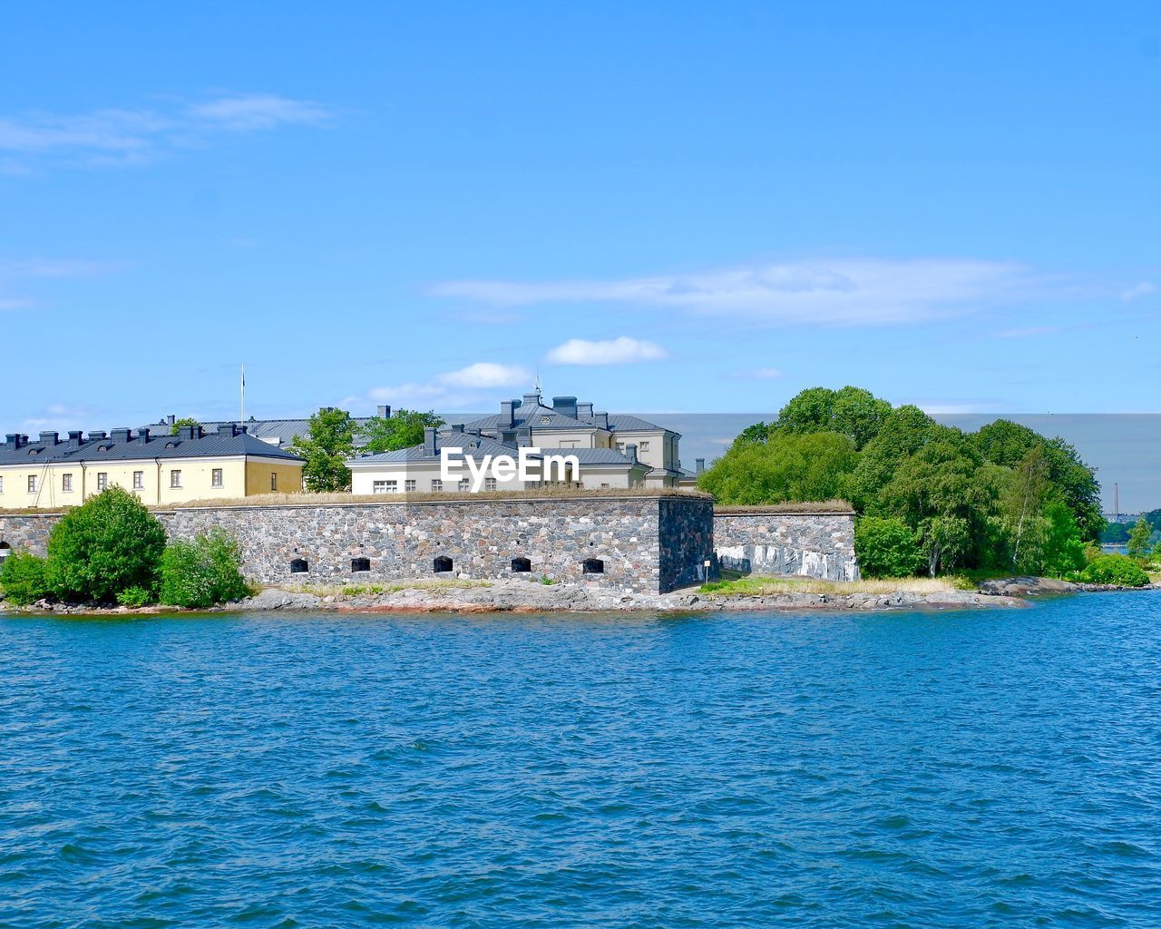 Buildings by sea against blue sky