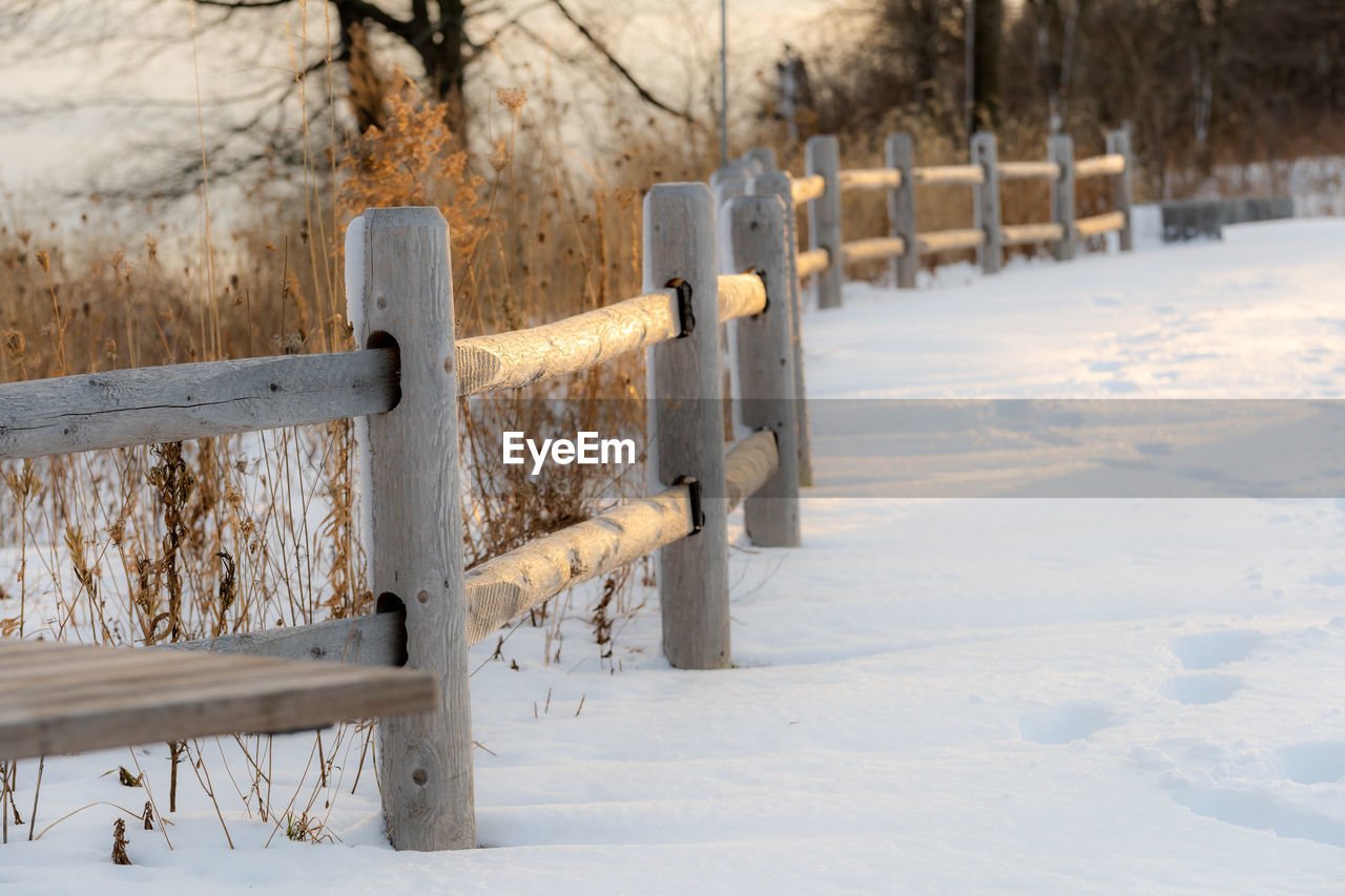 Wooden fence on snow covered field