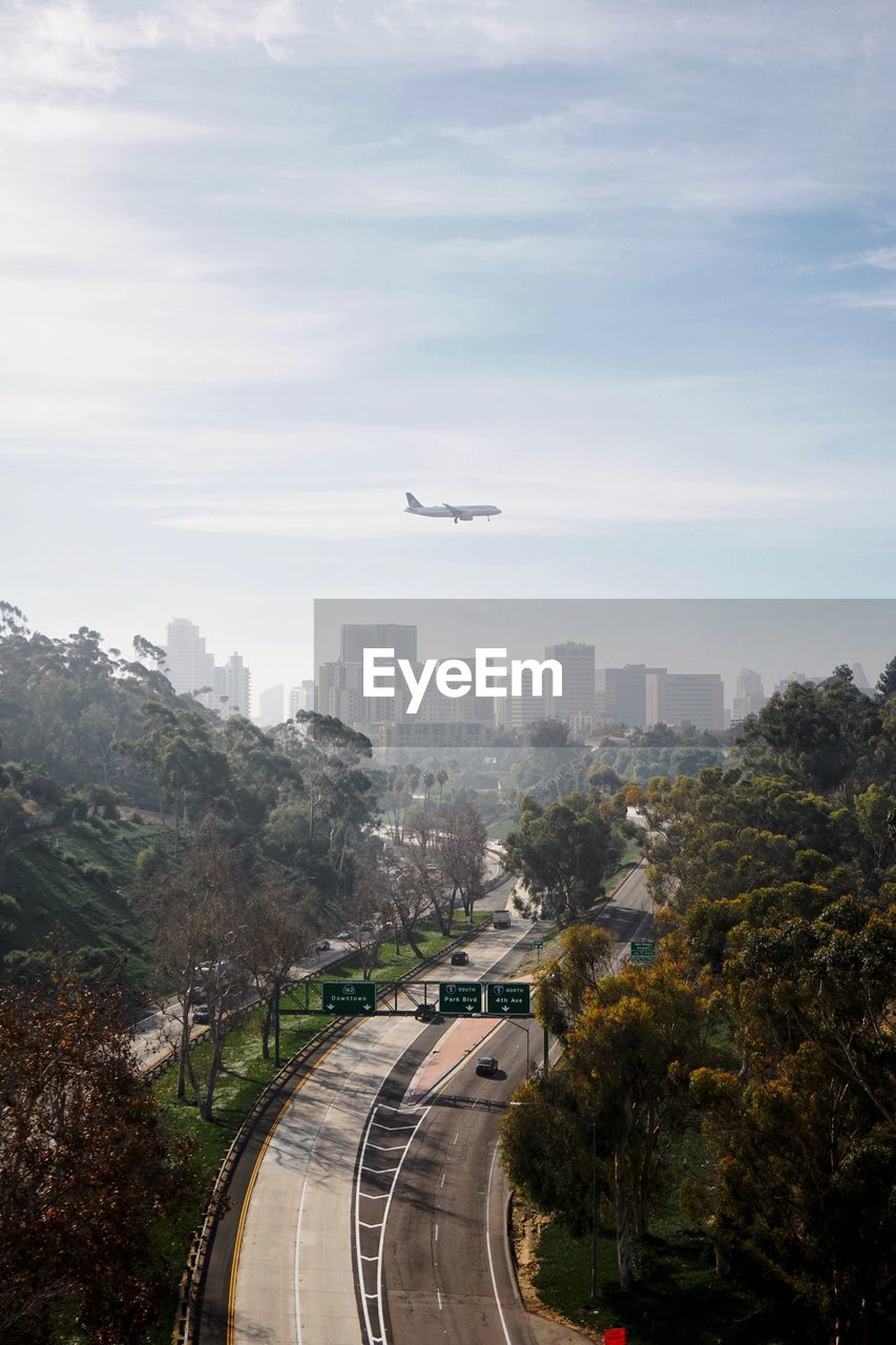 Airplane flying over city against sky