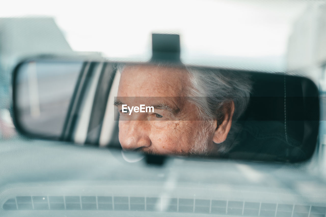 Reflection of senior man seen through rear view mirror