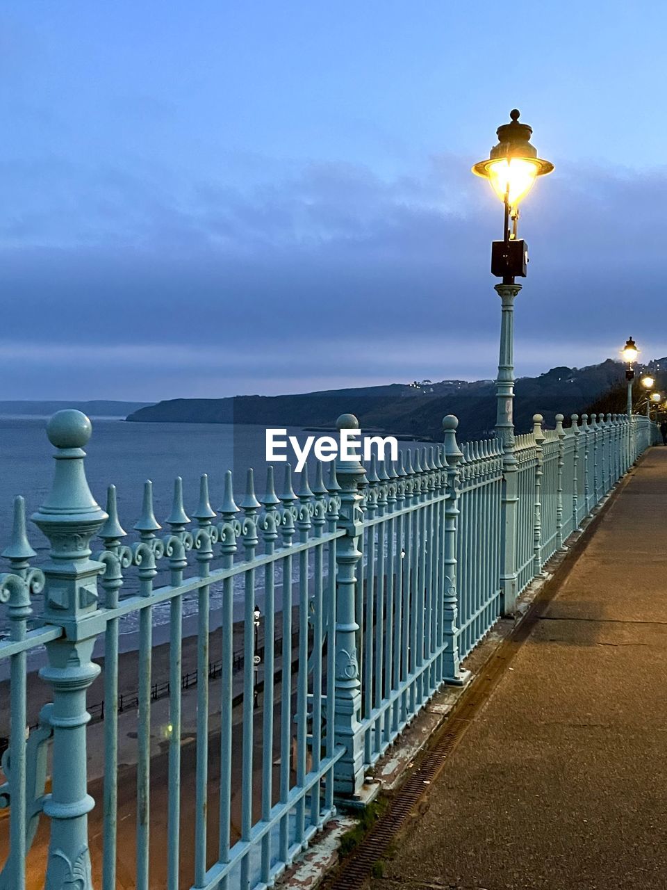 sky, water, sea, walkway, nature, architecture, railing, lighting equipment, street light, travel destinations, beach, pier, street, beauty in nature, land, cloud, travel, coast, scenics - nature, city, fence, no people, tourism, built structure, tranquility, horizon, outdoors, blue, landscape, environment, horizon over water, tranquil scene, security, ocean, coastline, holiday, illuminated, building exterior, sunset, footpath, transportation, dusk, protection, boardwalk, trip, vacation, idyllic