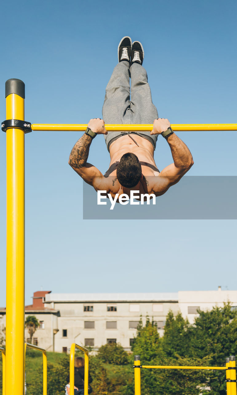 LOW ANGLE VIEW OF MAN JUMPING AGAINST CLEAR SKY