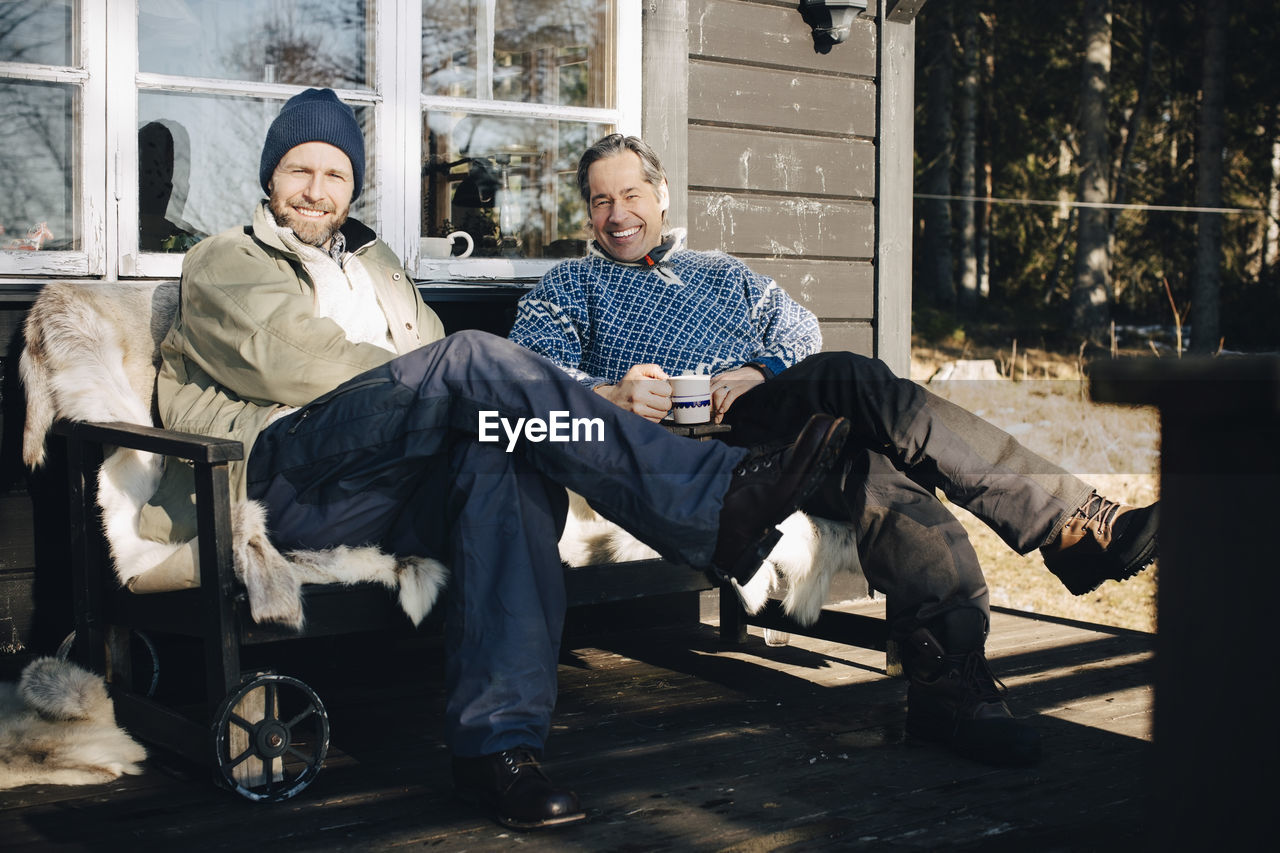 Full length portrait of happy mature men sitting together at front porch