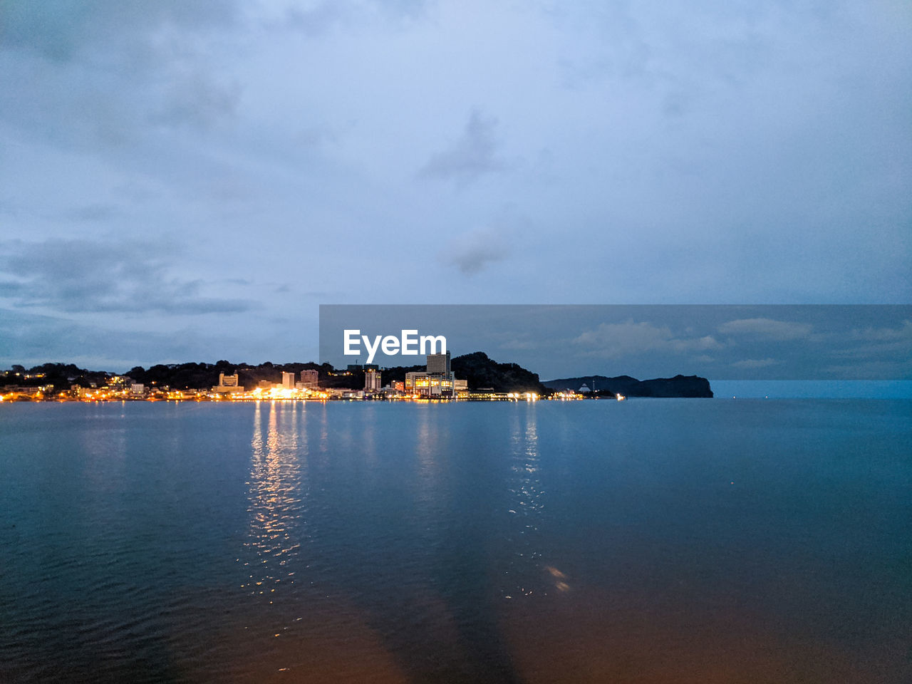 SEA BY BEACH AGAINST SKY AT DUSK