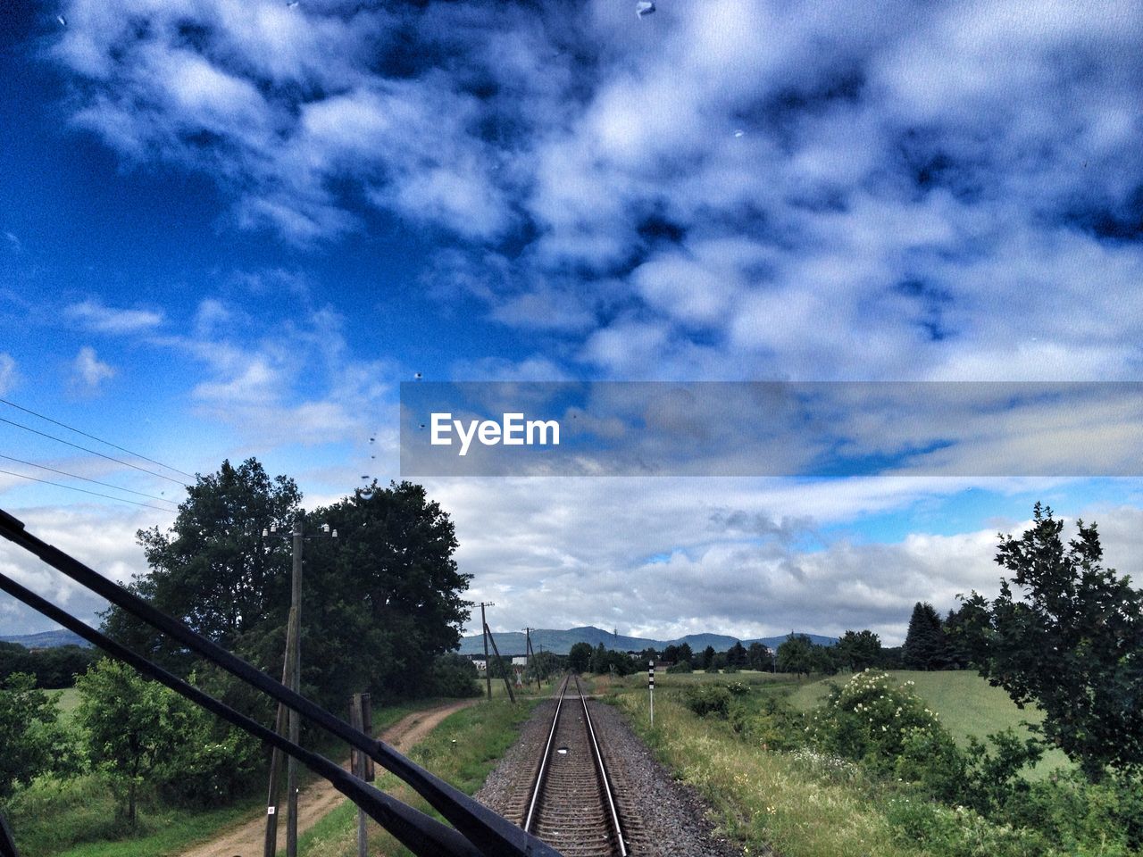 VIEW OF RAILROAD TRACK AGAINST CLOUDY SKY