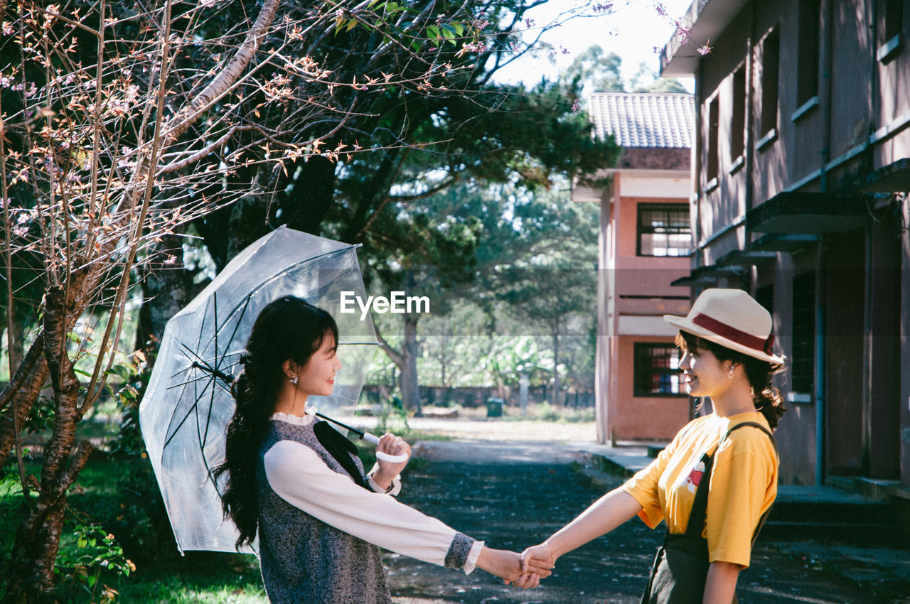 Friends shaking hands against houses and trees