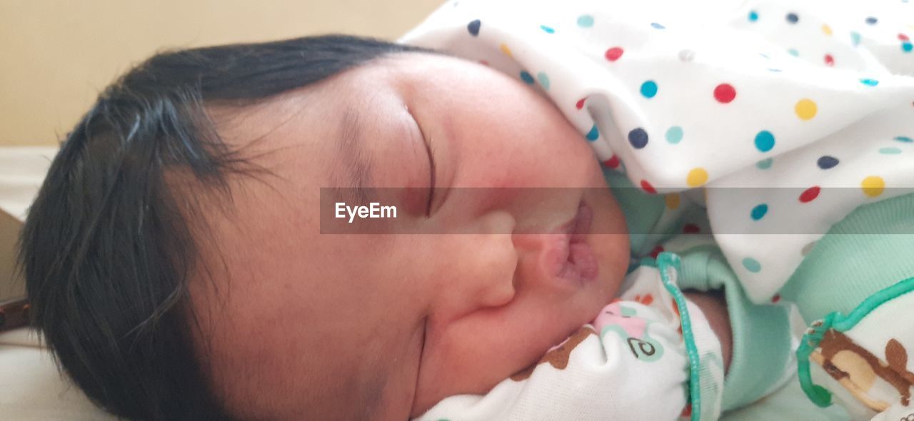 CLOSE-UP PORTRAIT OF CUTE BABY SLEEPING ON BED