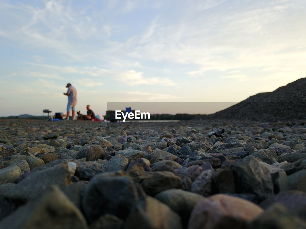 Men at beach against sky during sunset