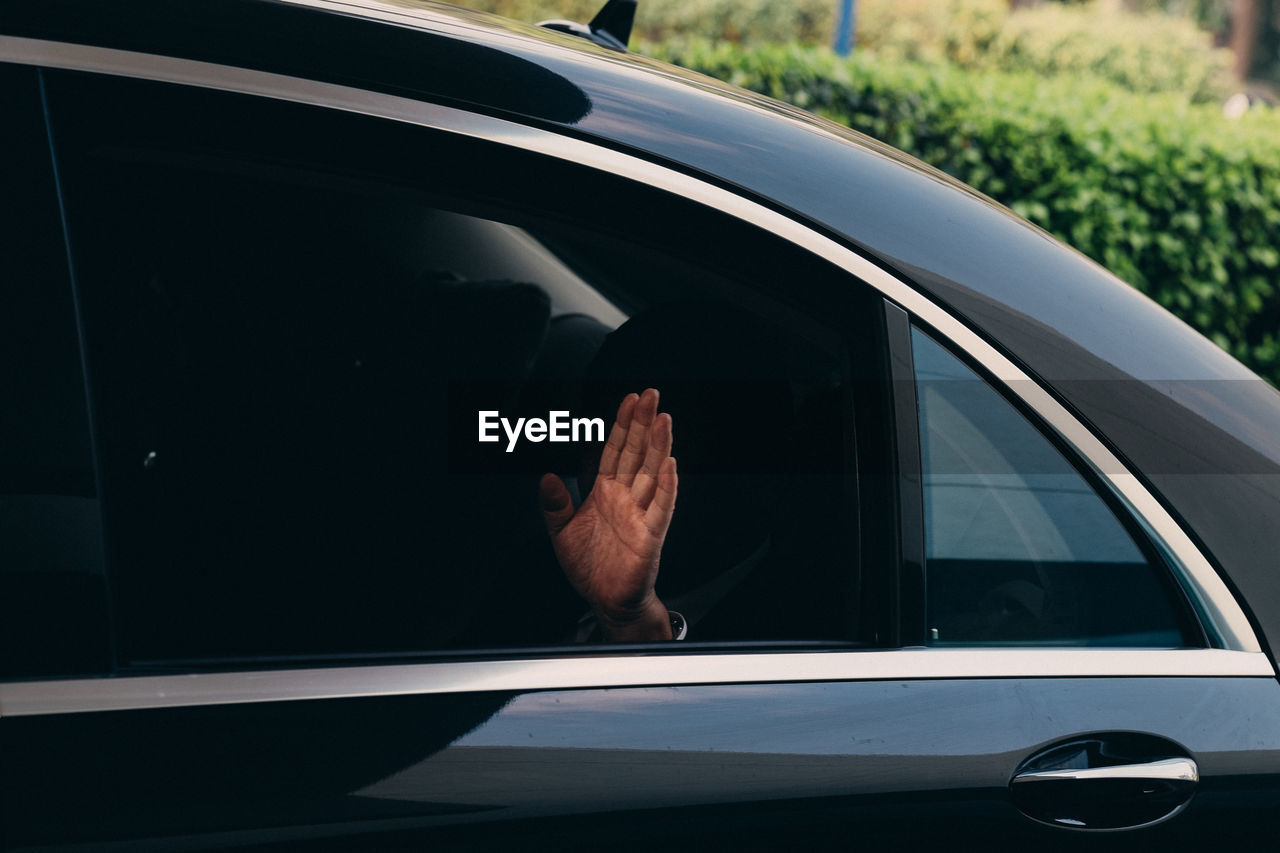 Cropped image of man waving hand in car