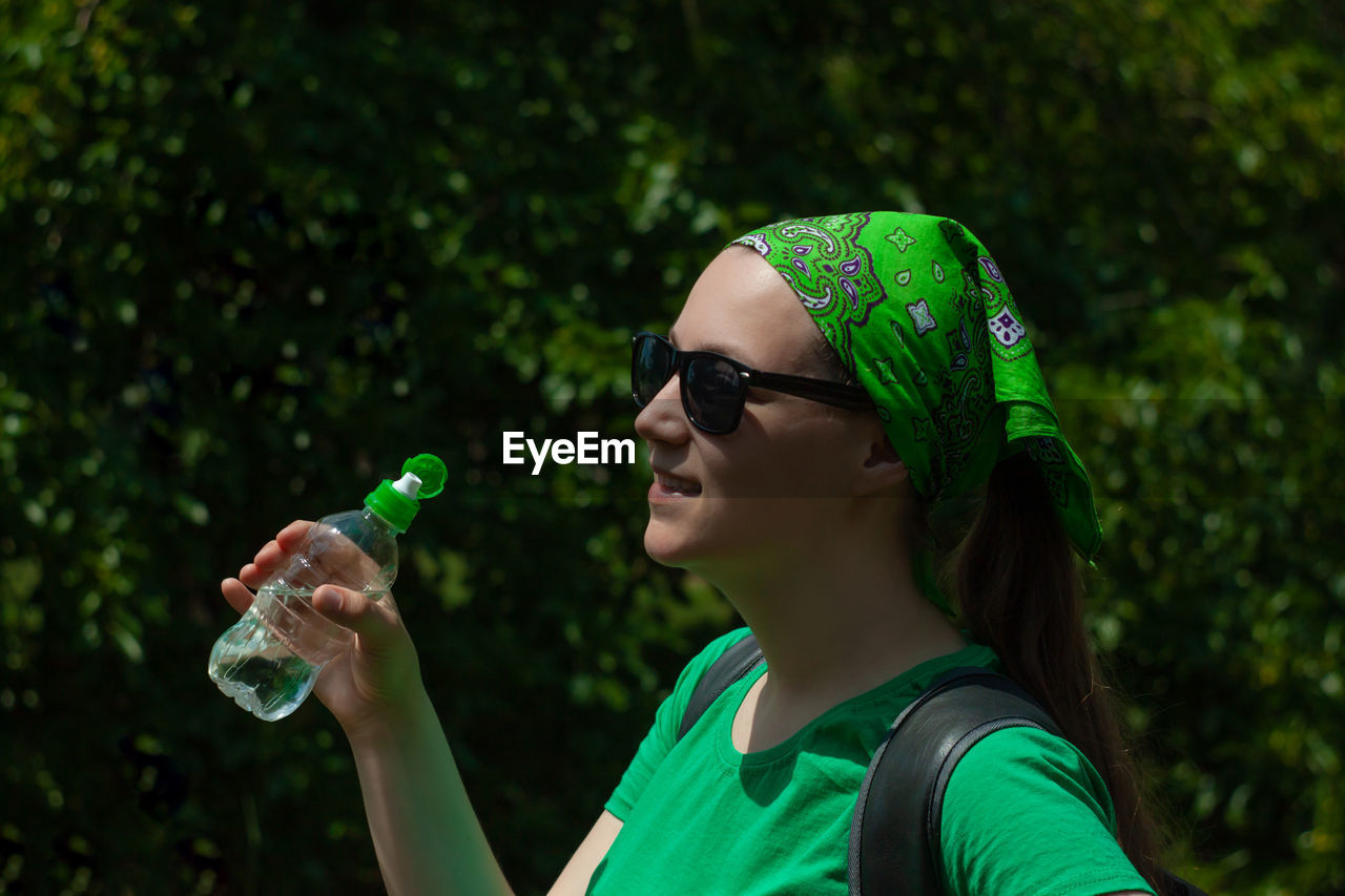 Young girl holds a bottle of water in hand and drinks weight loss, summer active lifestyle body care