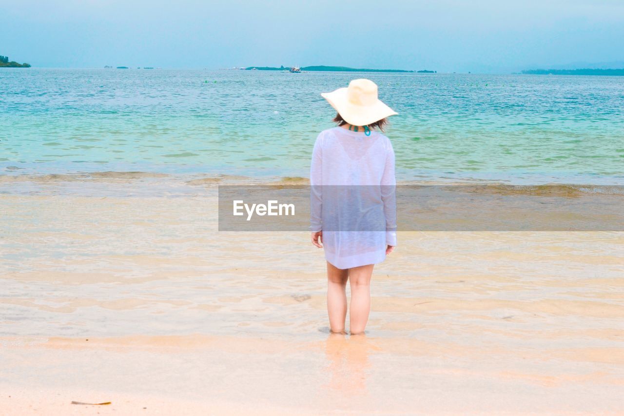 Rear view of woman standing in sea at beach