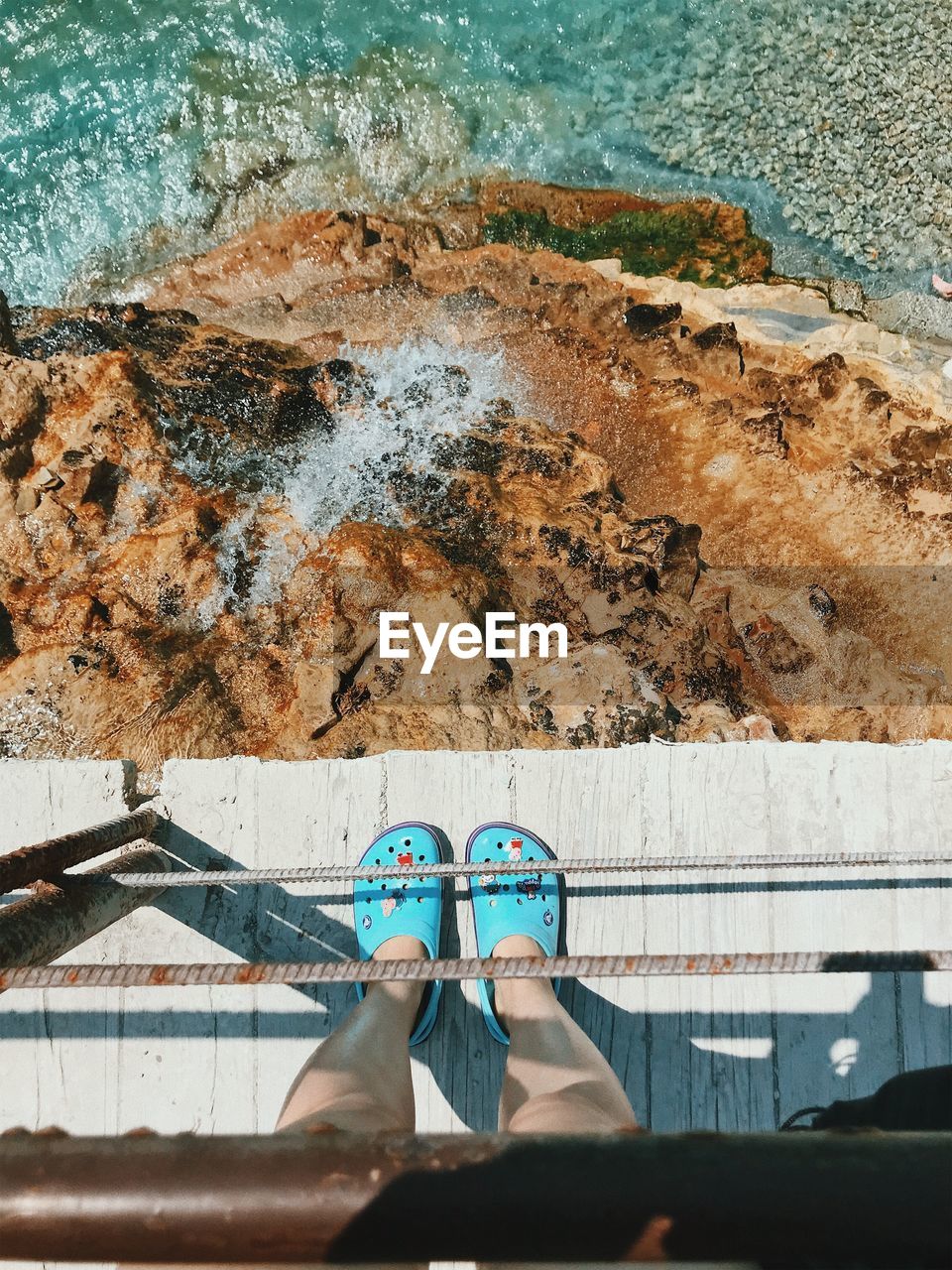 Low section of person standing on bridge over beach
