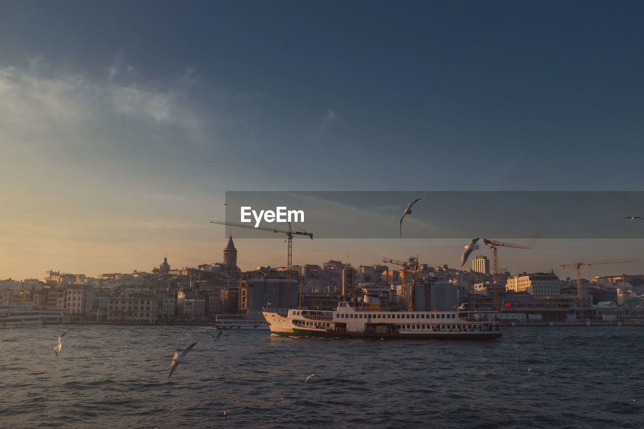 COMMERCIAL DOCK BY BUILDINGS AGAINST SKY DURING SUNSET