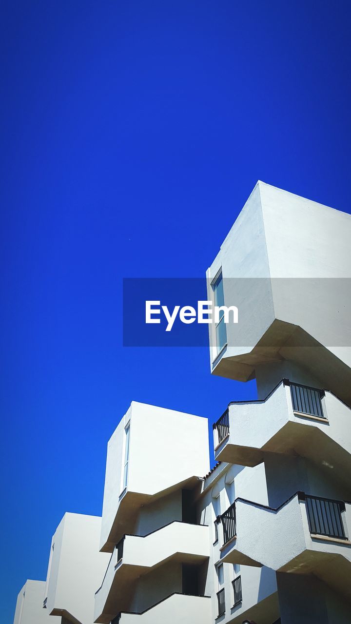 Low angle view of modern building against blue sky