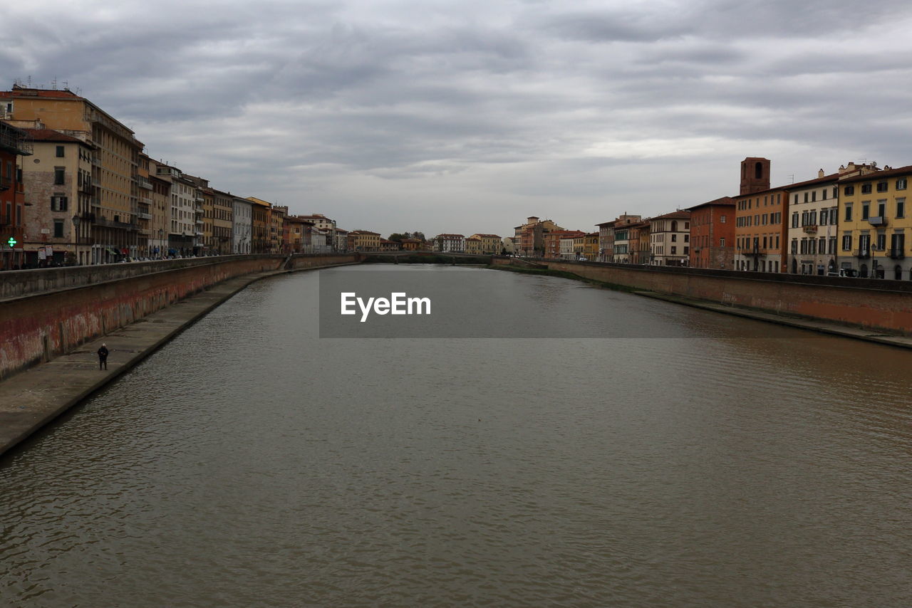 Bridge over river amidst buildings in city against sky