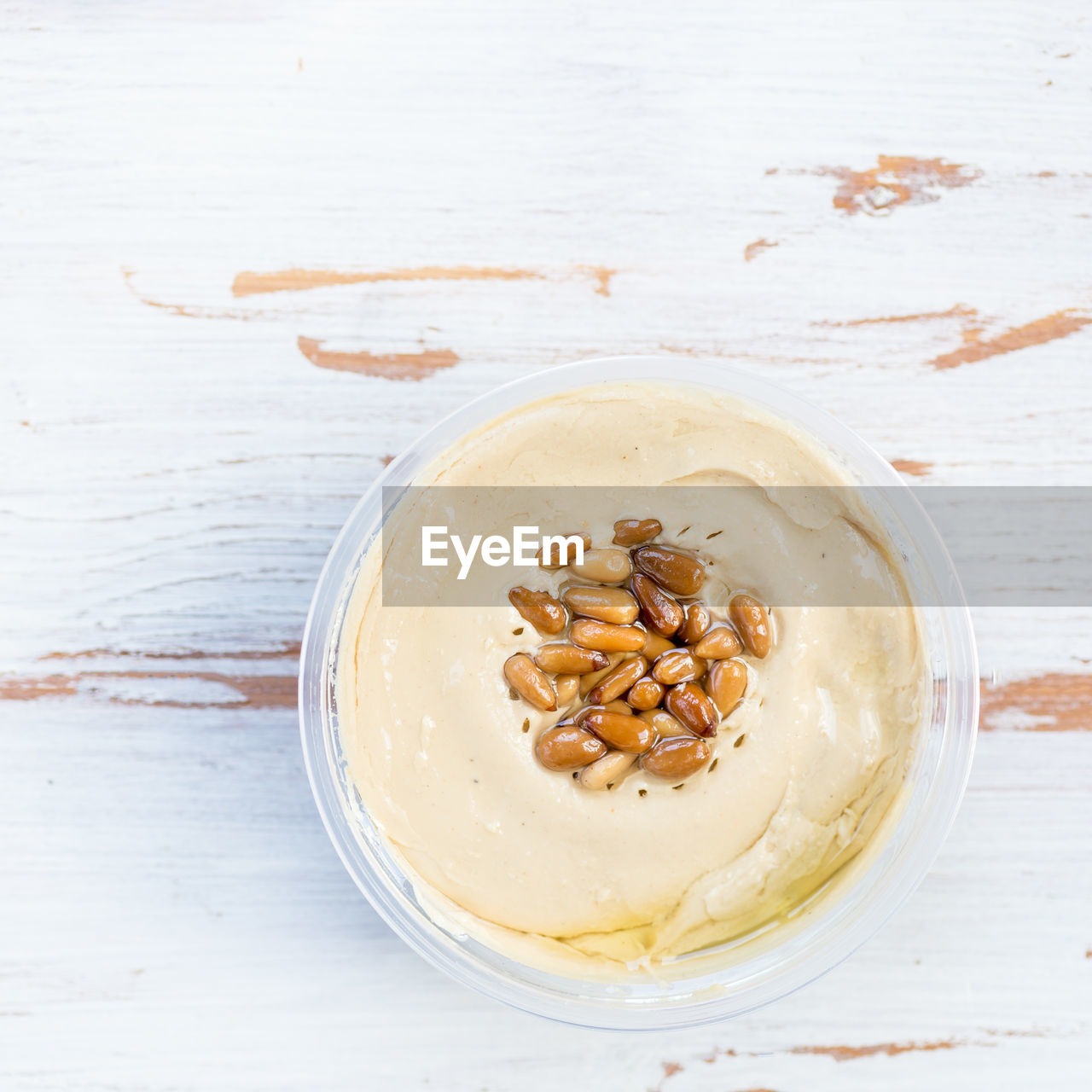 Classic hummus made from chickpeas with pine nuts on top, wooden rustic background, top view