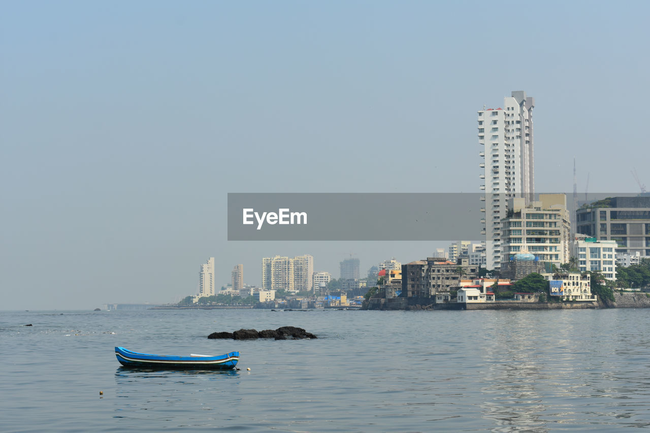 NAUTICAL VESSEL ON SEA BY BUILDINGS AGAINST SKY