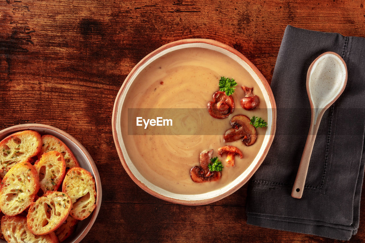 Mushroom cream soup with toasted bread, on a dark rustic wooden background