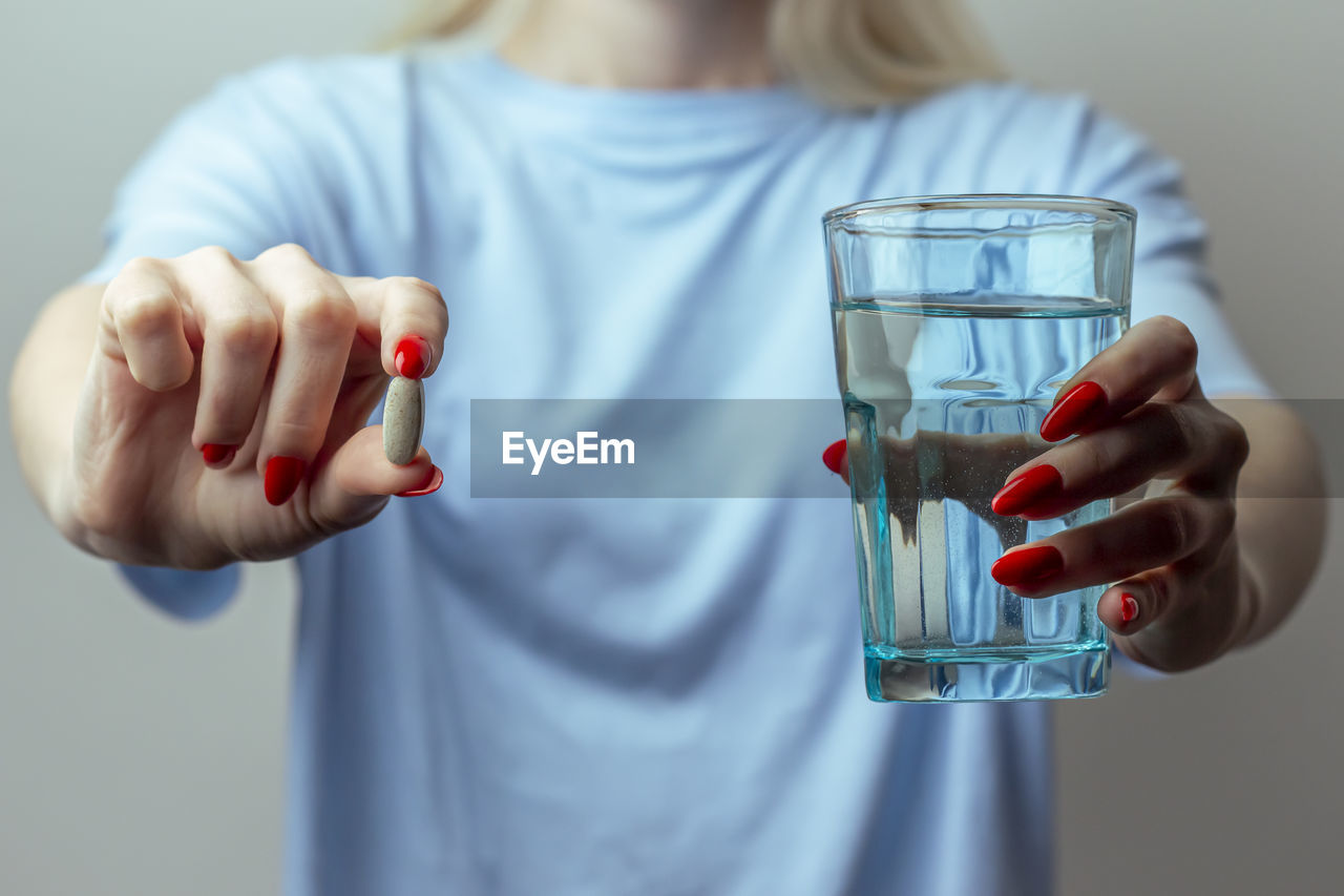 A woman holds a pill and glass of water i hands. health, medicine. treatment of diseases with drugs. 