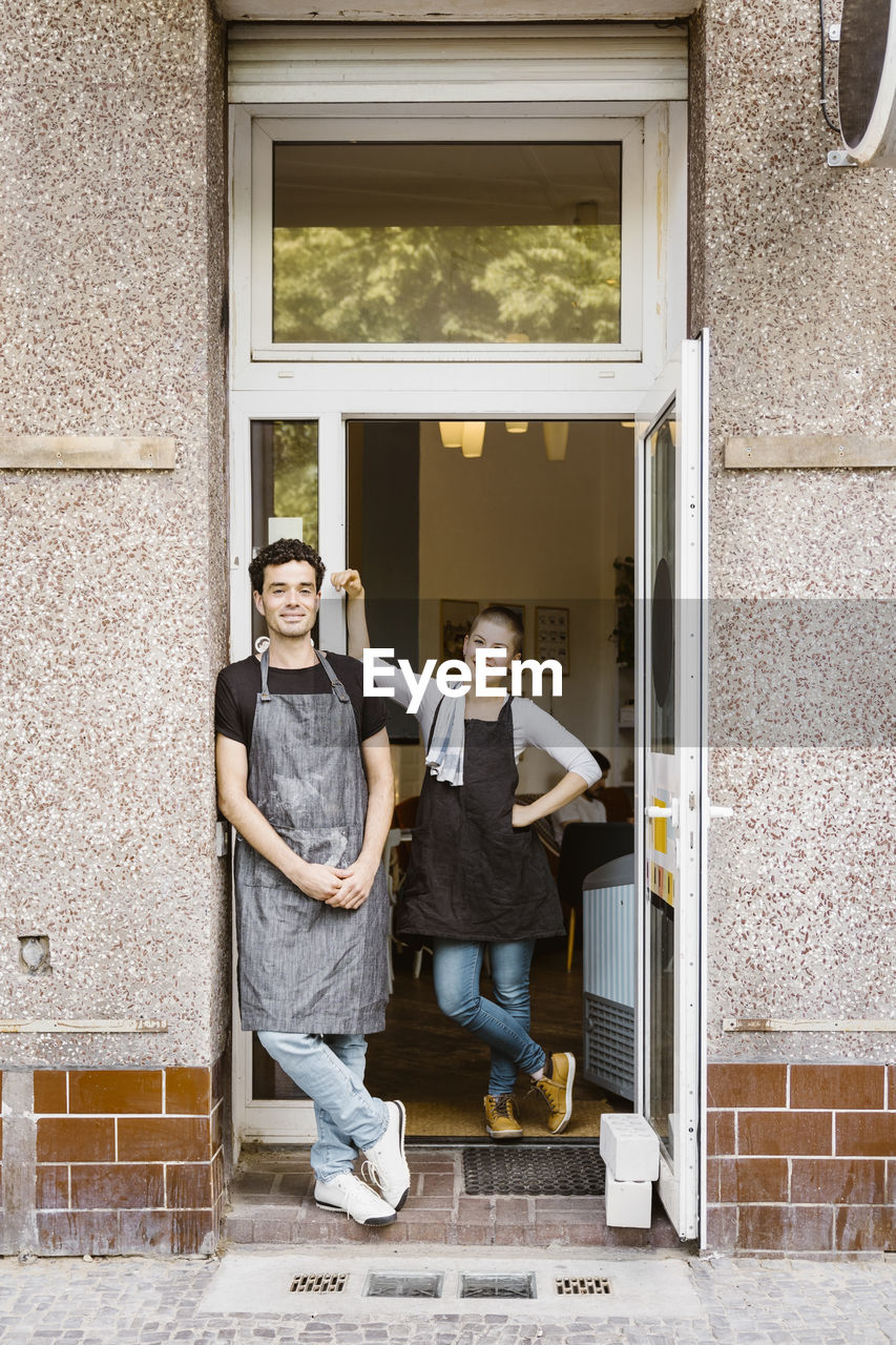 Male and female owners standing together near cafe doorway