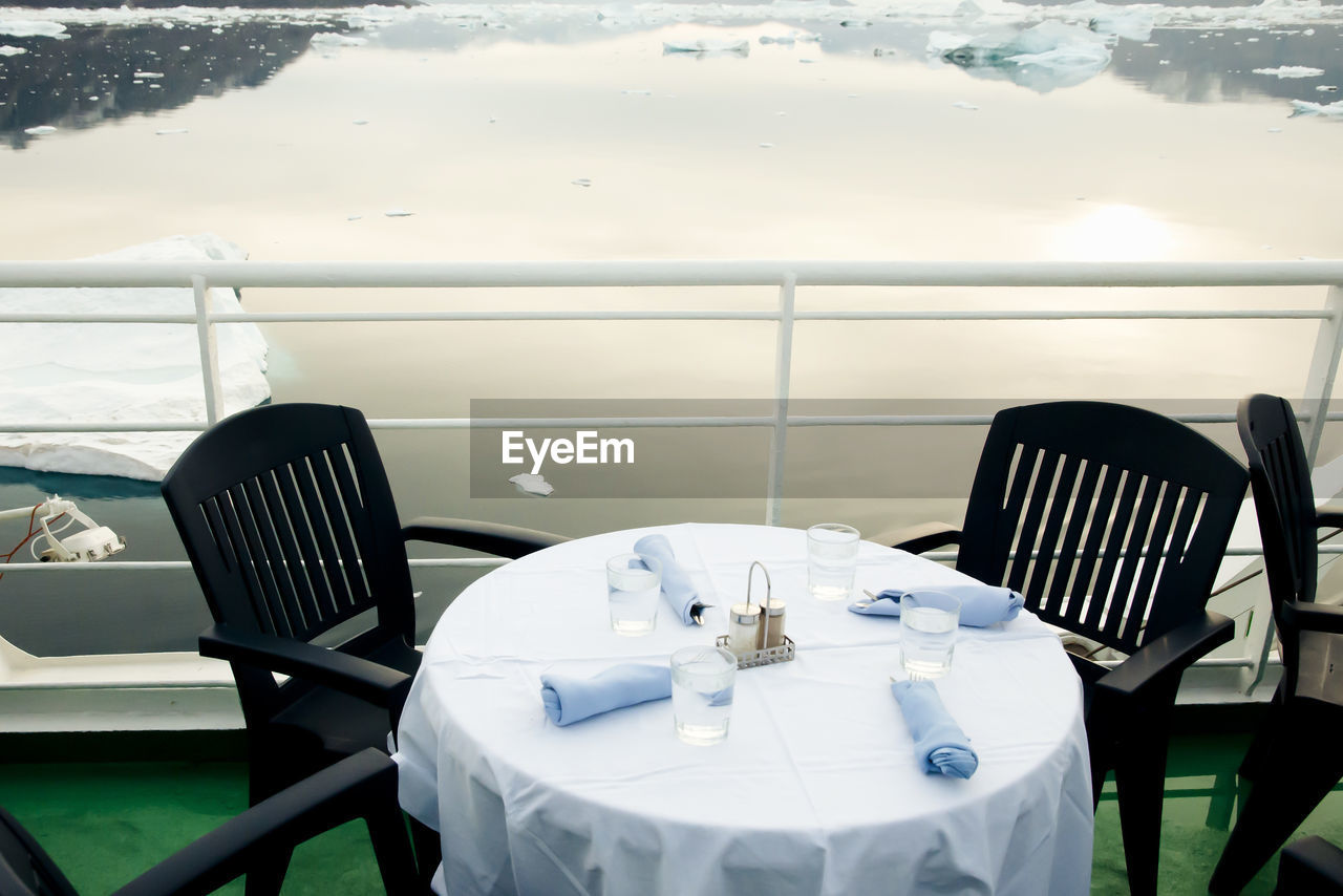 Empty chairs and tables by frozen lake in restaurant