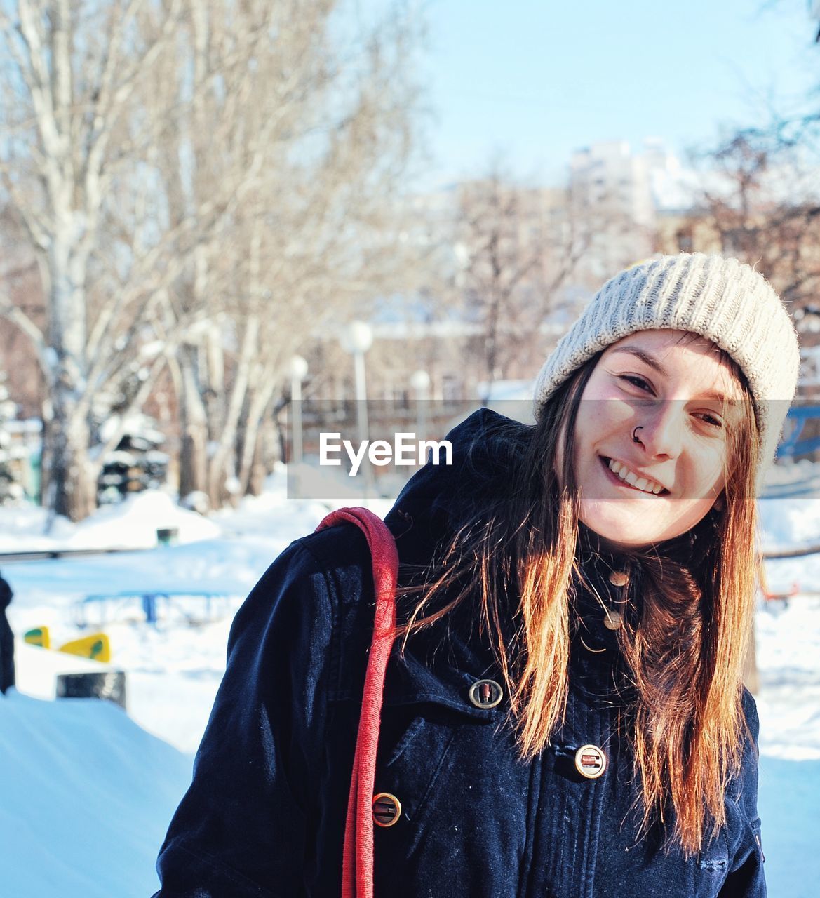 Portrait of young woman with bond hair wearing warm clothing on snowy field