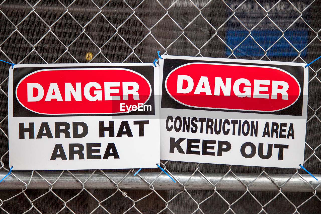 Warning sign on fence at construction site