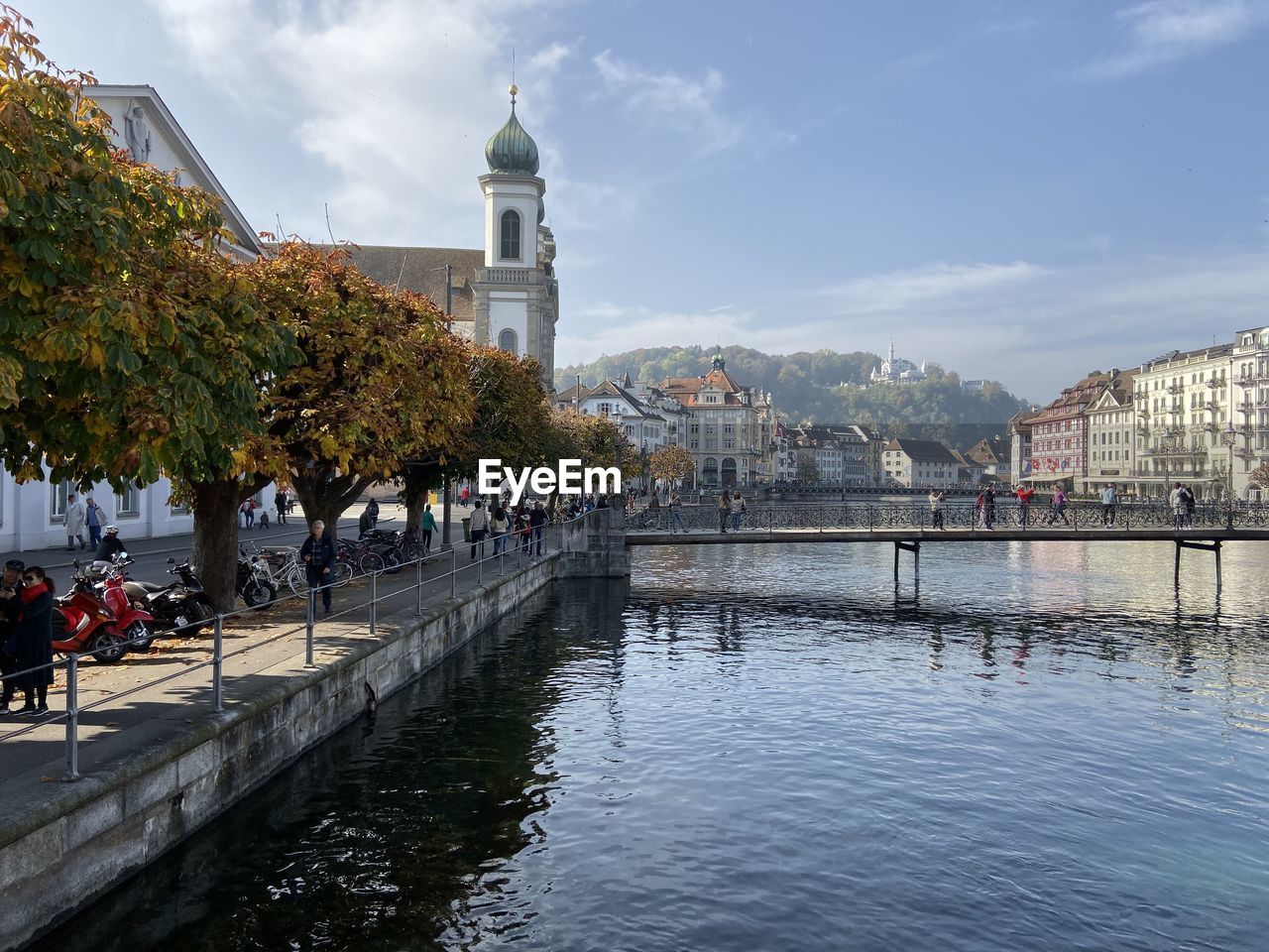 People on river by buildings in city