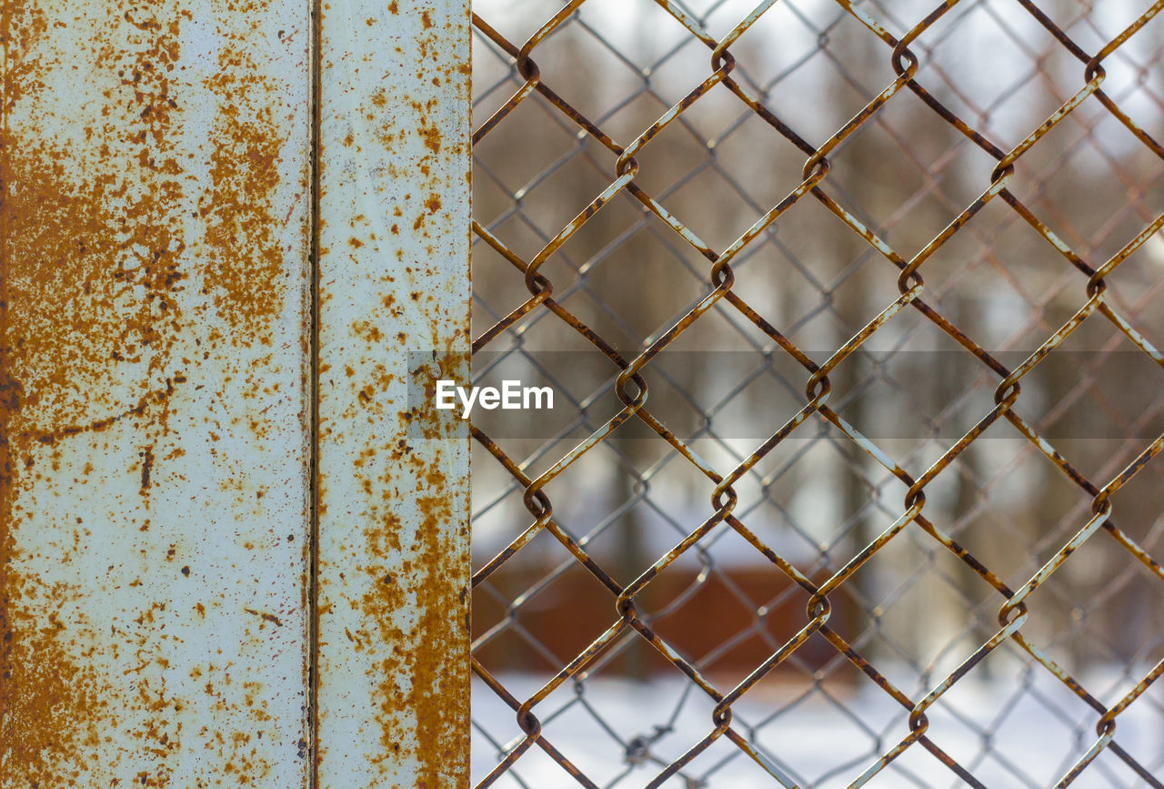 The fence is made of rusty chain-link mesh
