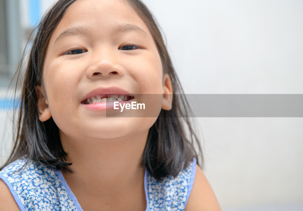 Asian kid girl smile and showing her broken milk teeth.