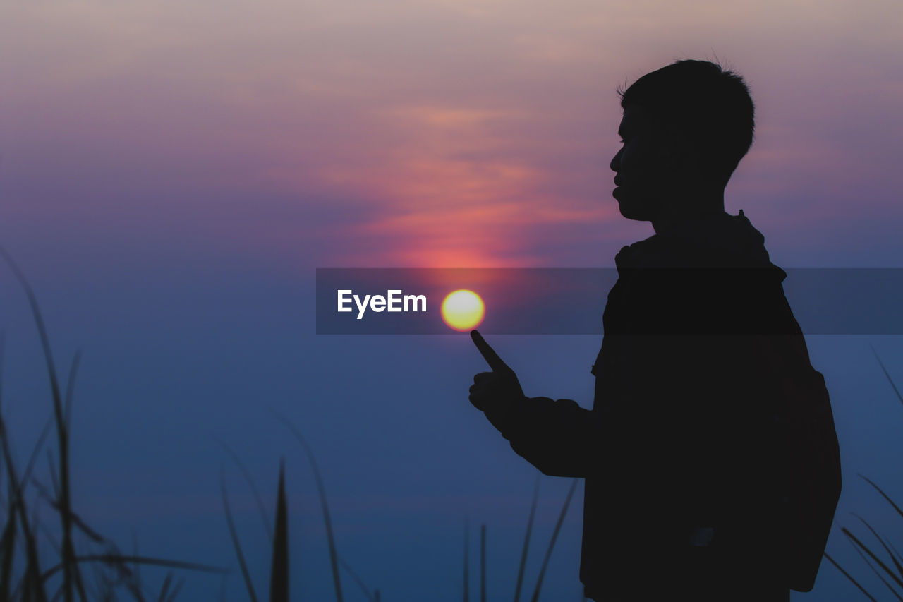 Silhouette man standing against sky during sunset