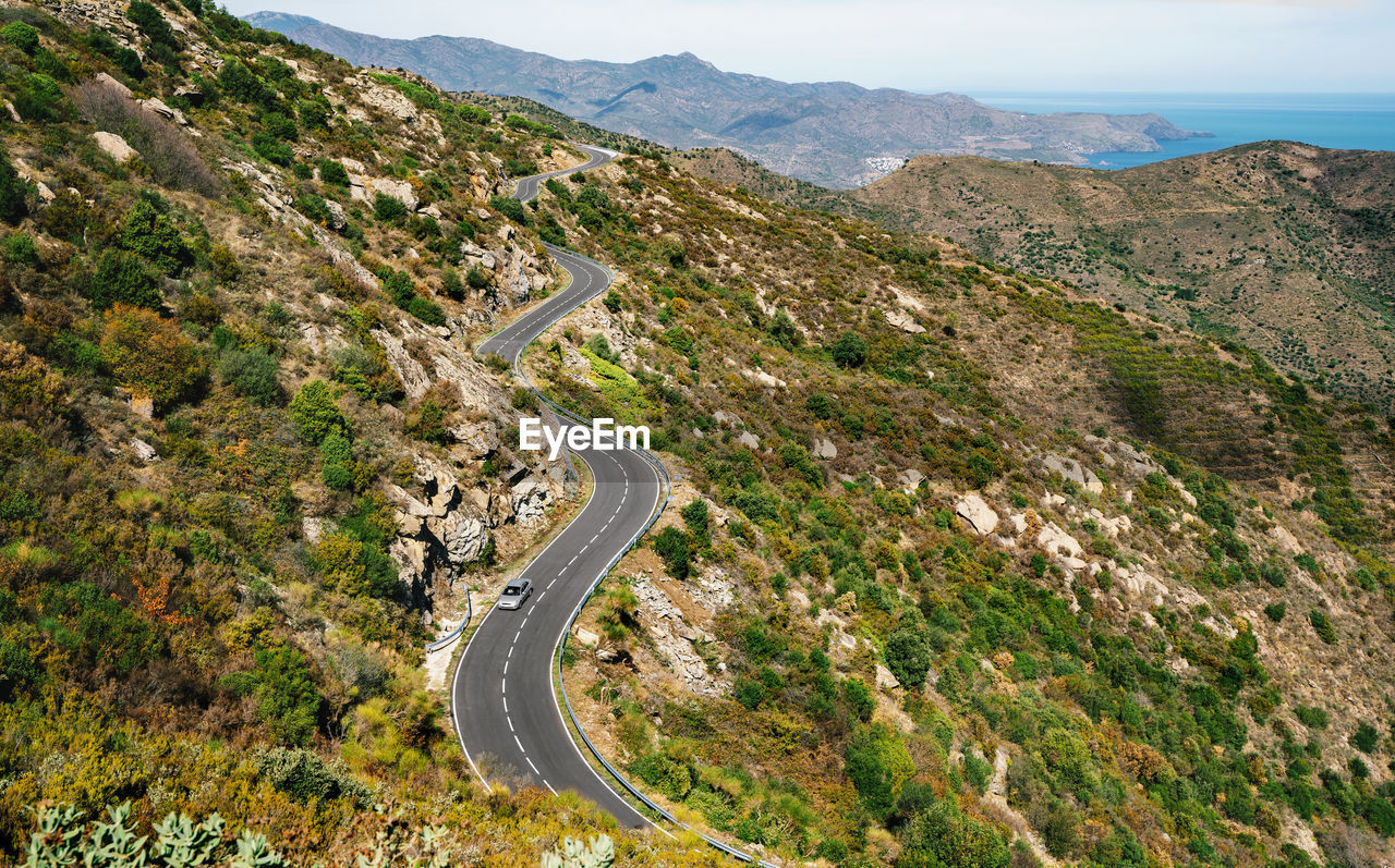 HIGH ANGLE VIEW OF ROAD BY MOUNTAINS