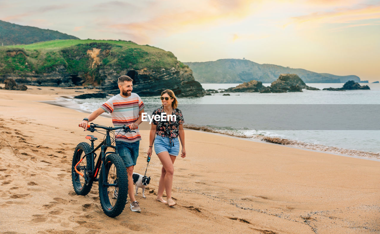 Couple with a fat bike taking a walk on the beach