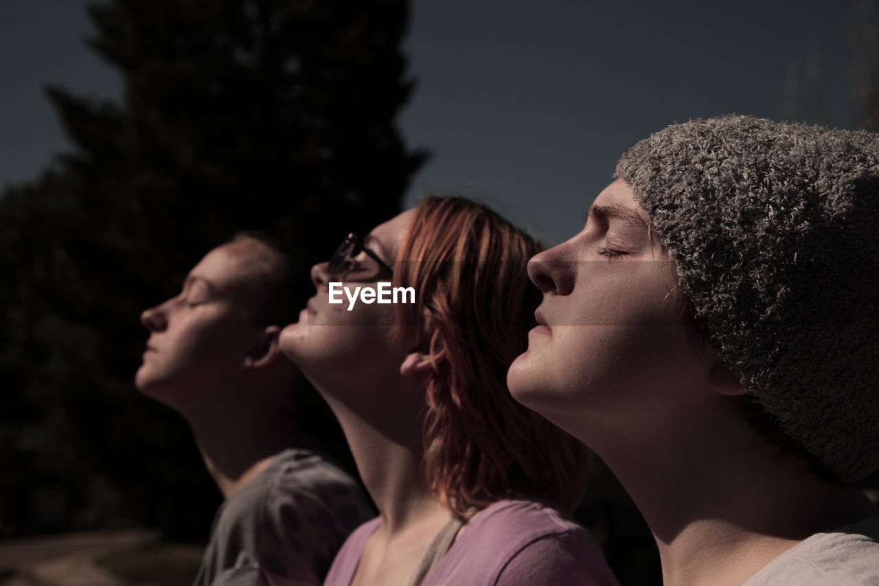 Sunlight falling on sisters with eyes closed during solar eclipse