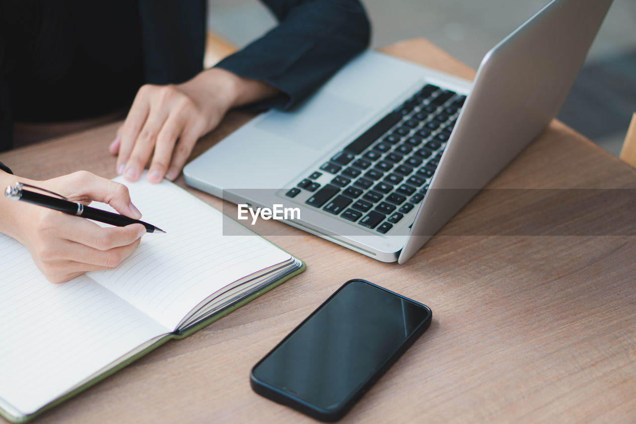 midsection of businessman using laptop on table