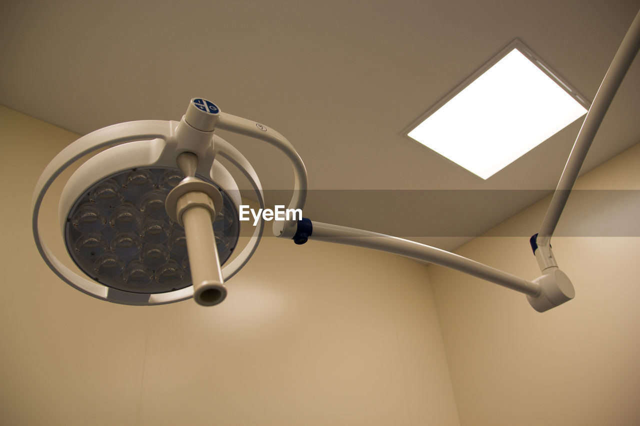 LOW ANGLE VIEW OF ELECTRIC LAMP HANGING AGAINST CEILING