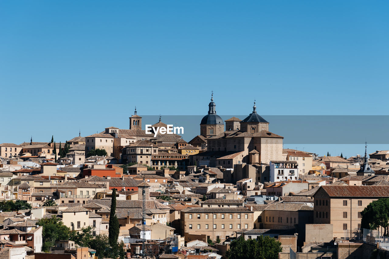 View of buildings in city against clear blue sky