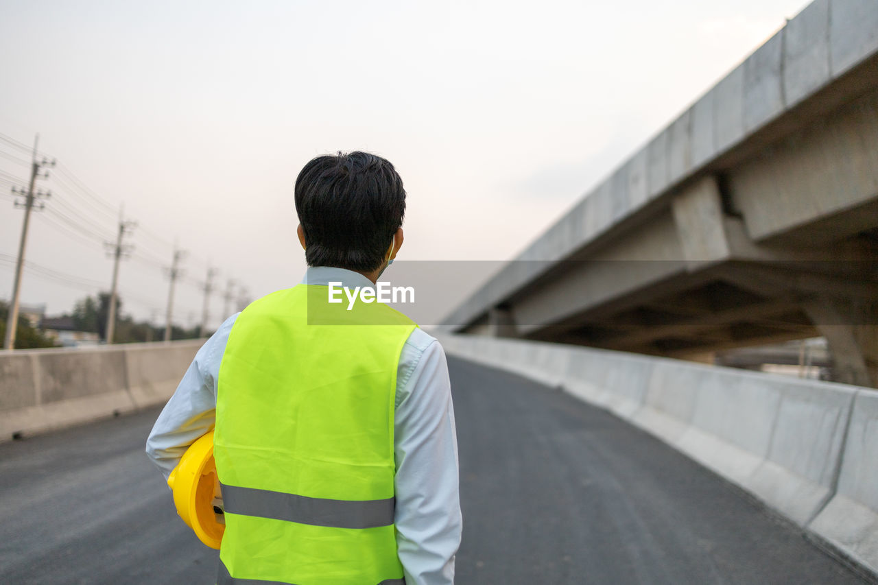 Rear view of man standing on bridge against sky